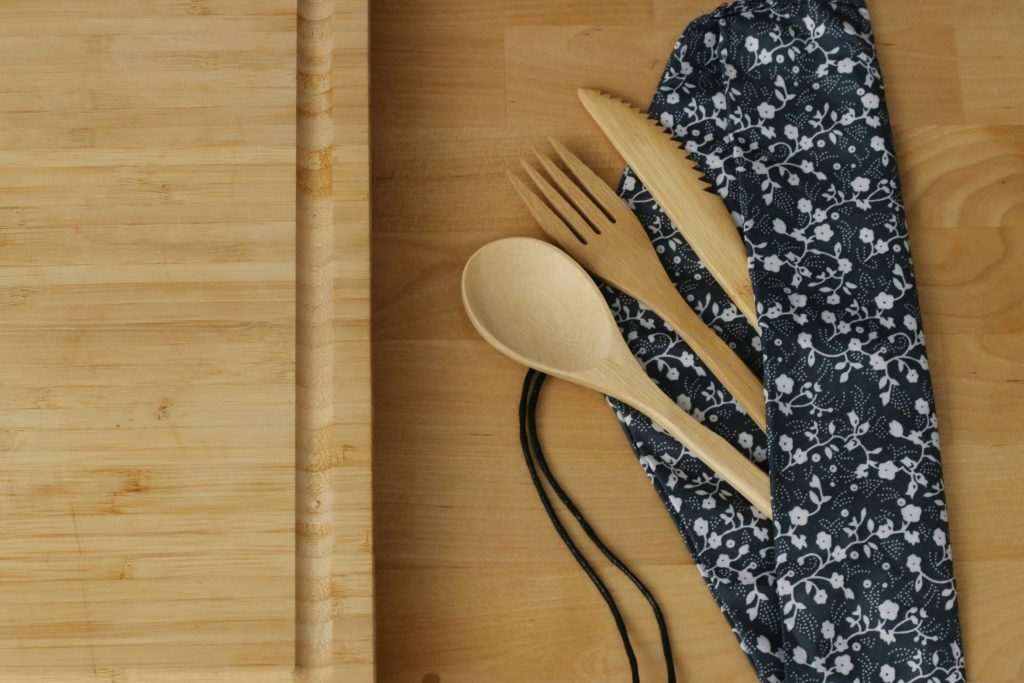 Zero-waste kitchen essentials with glass jars and bamboo tools on a bright counter.